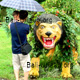 Mit dem Regenschirm vor dem dämonischen gelben Löwen beim Bali Urlaub